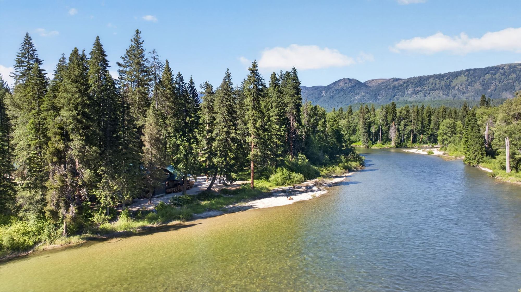 Aerial view of Rivers Edge Lodge and its private beach on the Wenatchee River, with mountains beyond
