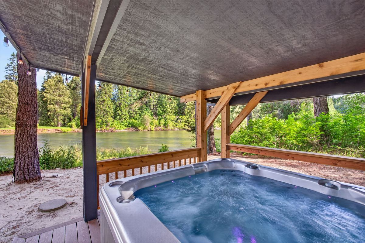 Covered hot tub with string lights overlooking the river