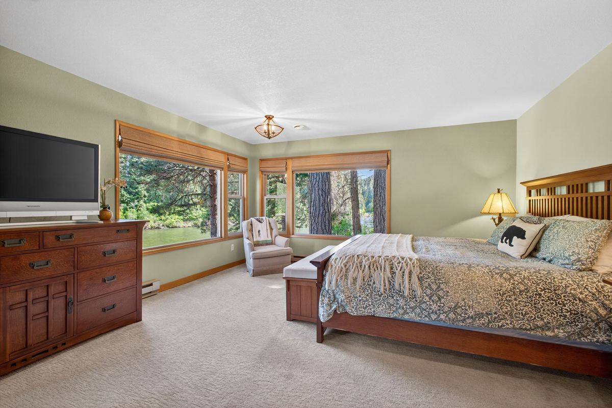 Primary suite with king bed, TV and windows overlooking the river
